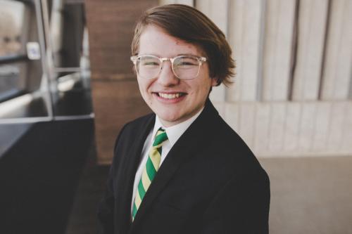 Picture of Addison Armstrong in a black suit with a nile green and old gold tie 